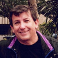 Steve-Walsh-crop A man with a black jacket and purple collar.
