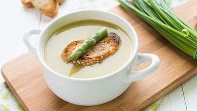 A bowl of soup with bread and green beans.